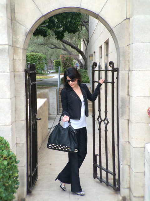 Brunette In Black Leather Jacket And Blue Jeans Modeling Black Leather Bag And White Leopard Print Pumps